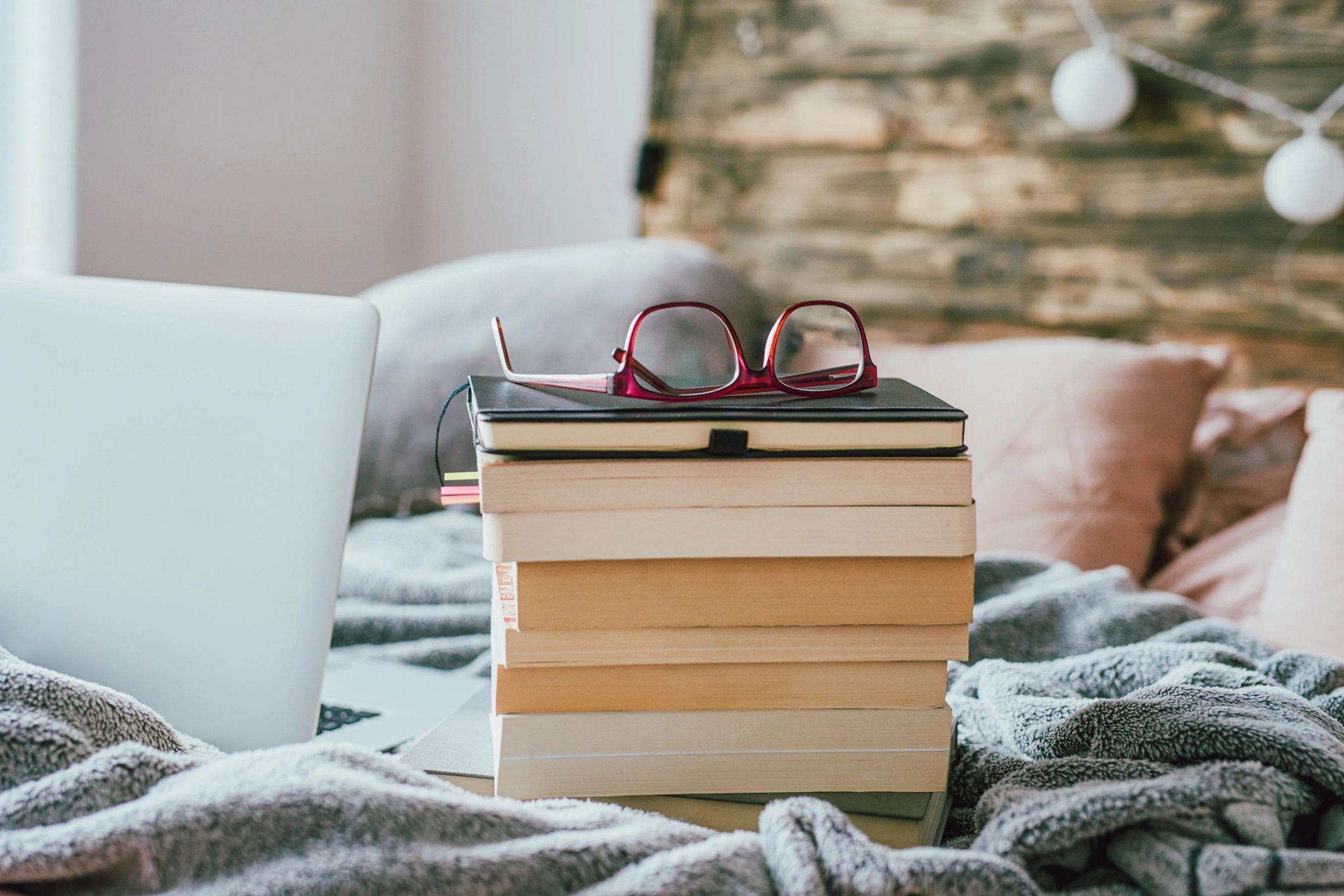 Stack of books with glasses and laptop
